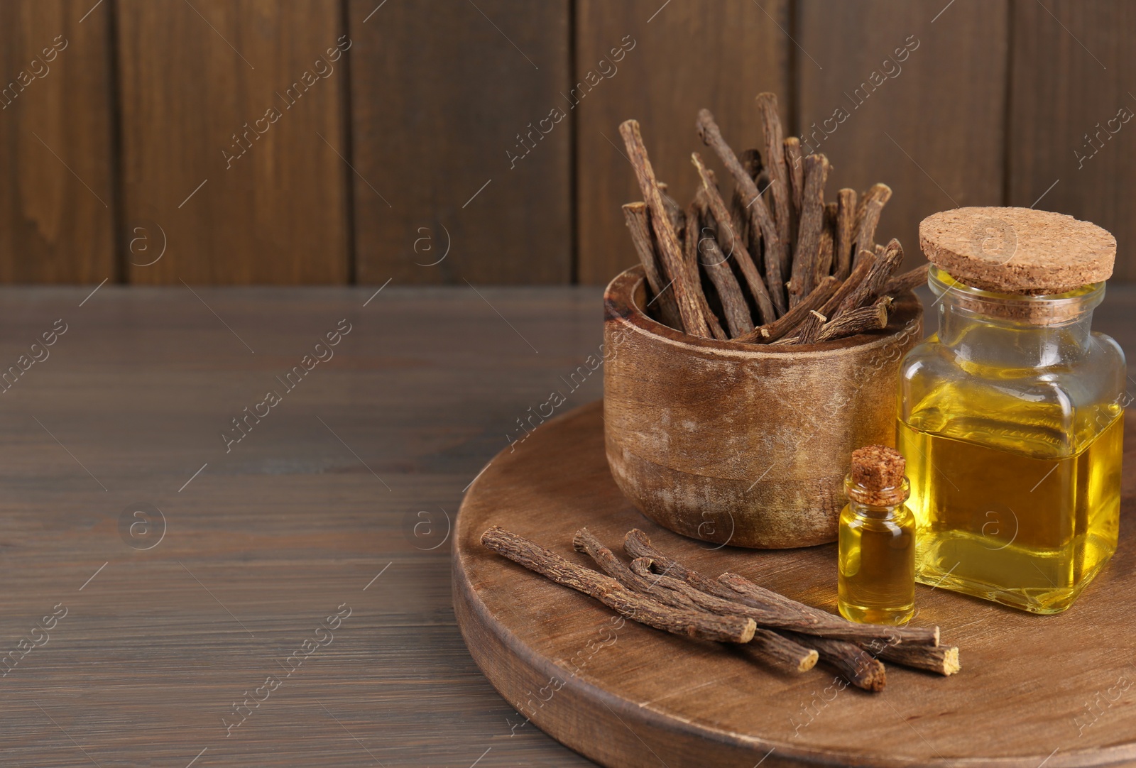 Photo of Dried sticks of licorice roots and essential oil on wooden table. Space for text