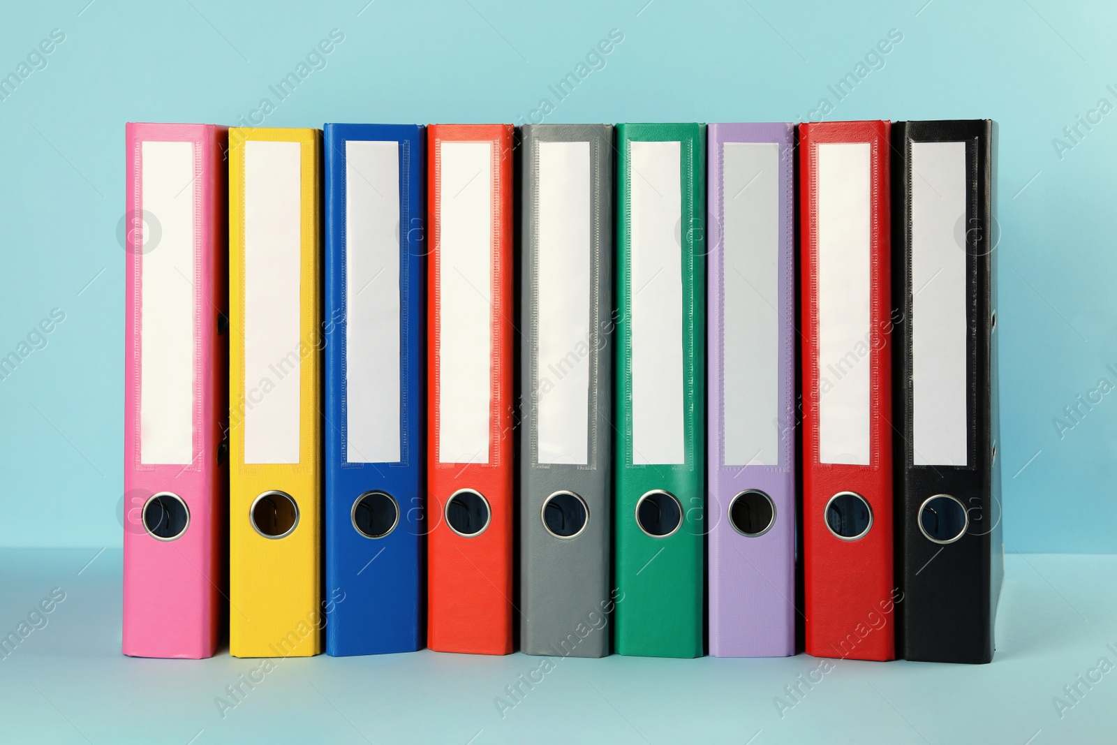 Photo of Many hardcover office folders on light blue background