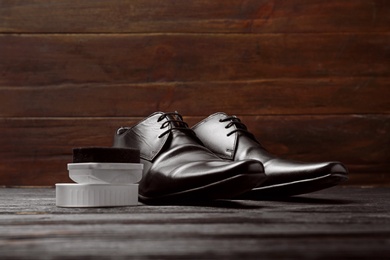 Photo of Leather shoes and cleaning sponge on dark wooden table