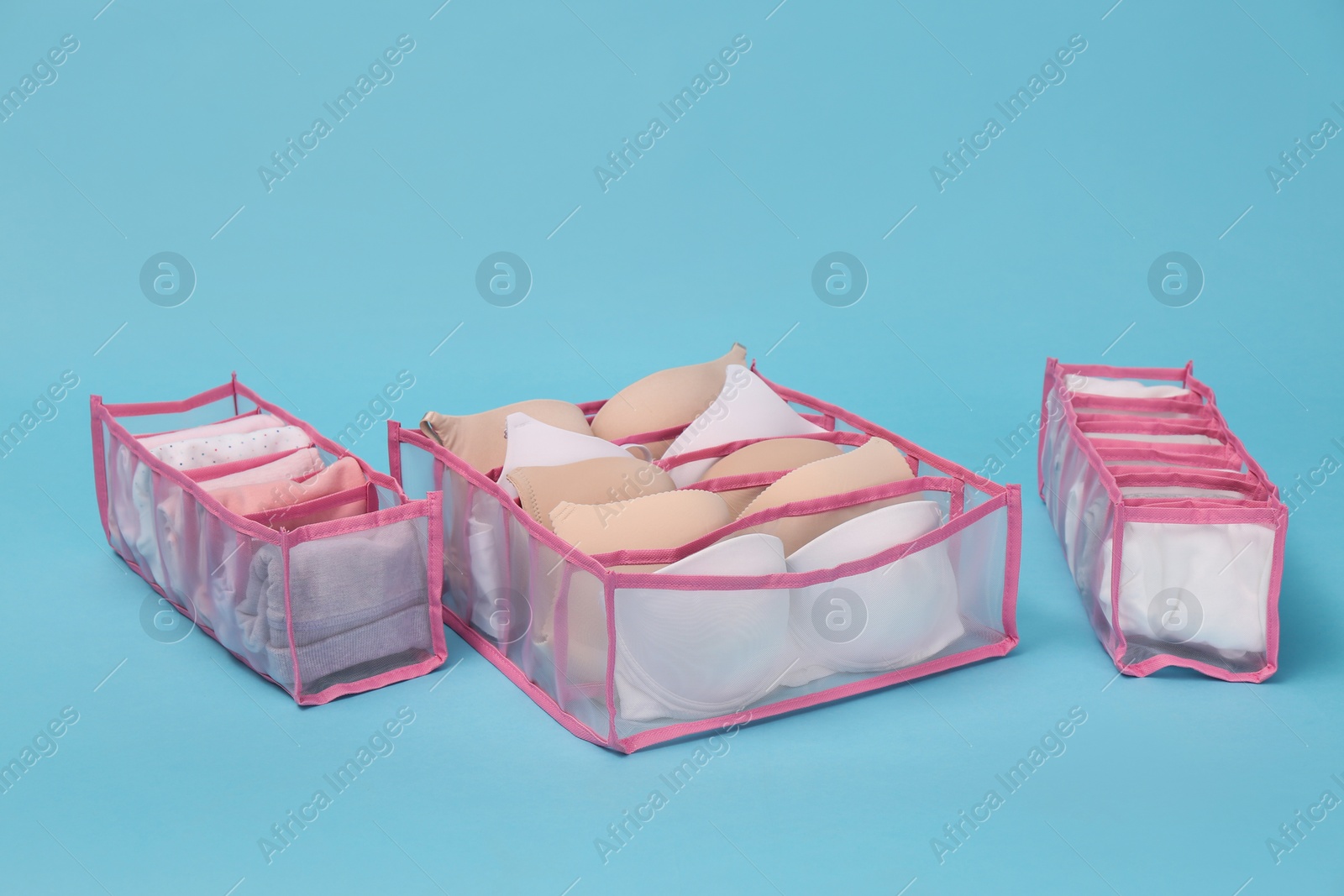 Photo of Transparent organizers with underwear on light blue background