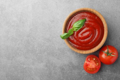 Photo of Bowl of tasty ketchup, tomatoes and basil on light grey table, flat lay. Space for text