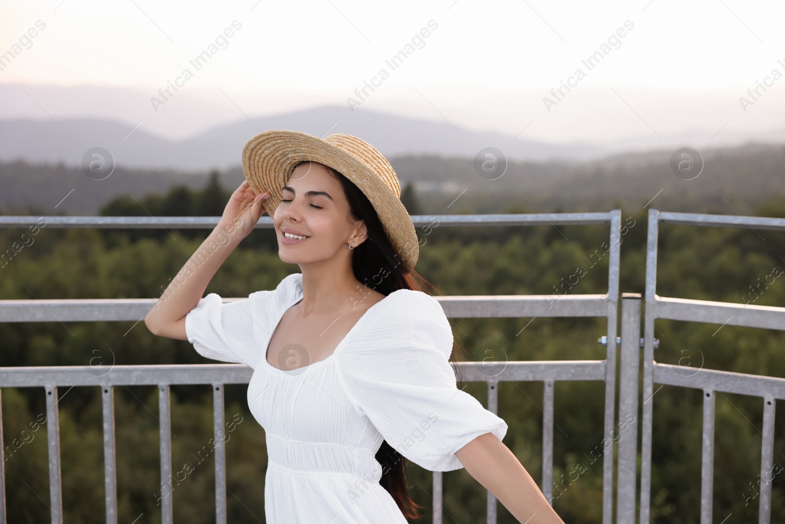 Photo of Feeling freedom. Happy woman enjoying nature near metal railing outdoors