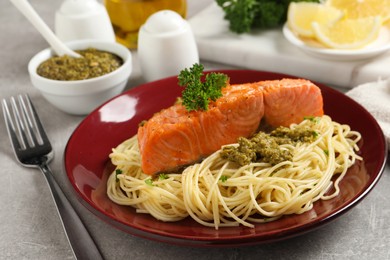 Photo of Delicious spaghetti with salmon and pesto sauce on light grey table, closeup