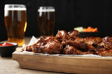 Photo of Tasty chicken wings on wooden table, closeup. Beer snack