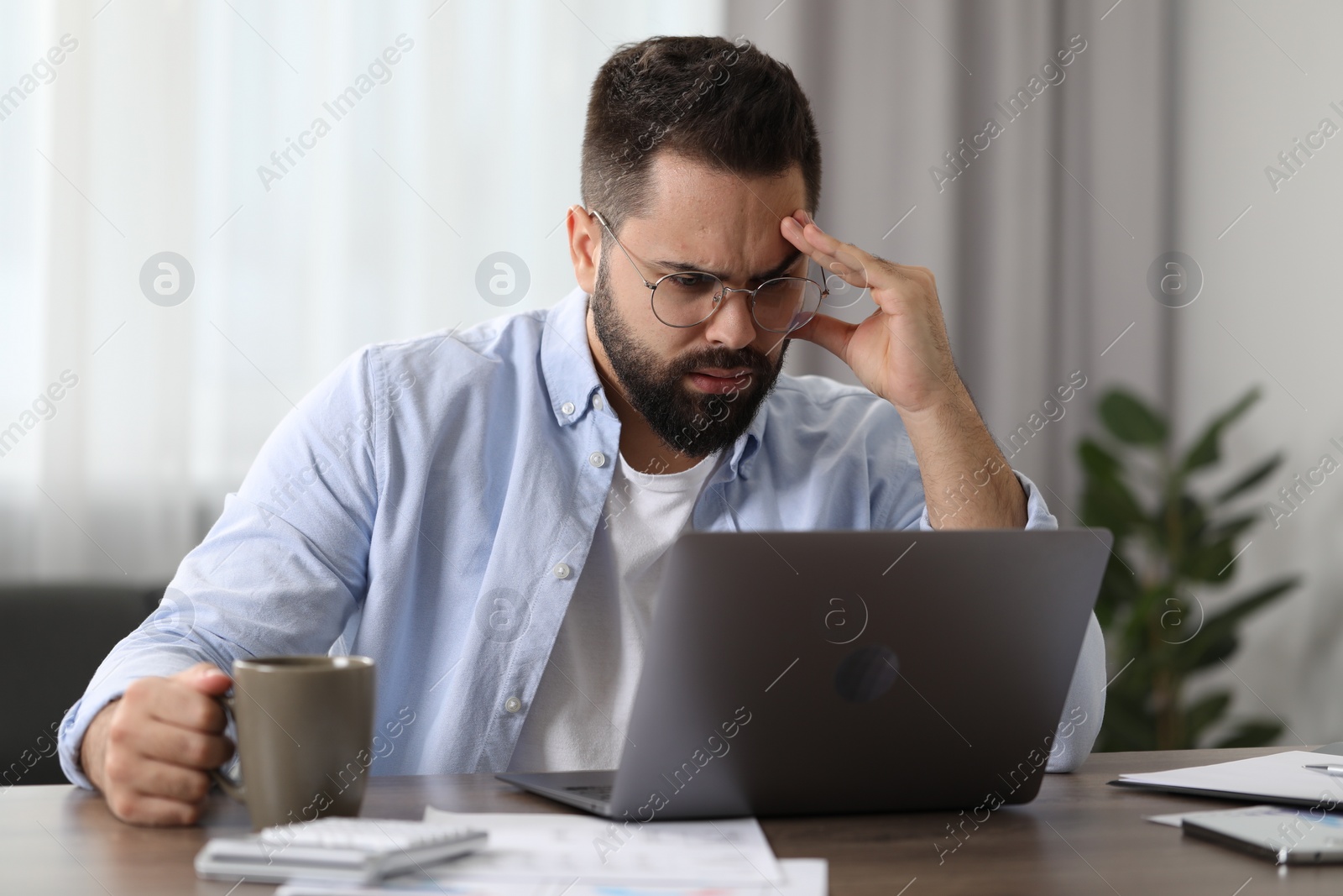 Photo of Man suffering from headache at workplace in office