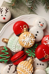 Photo of Beautifully decorated Christmas macarons and fir branches on white table, flat lay