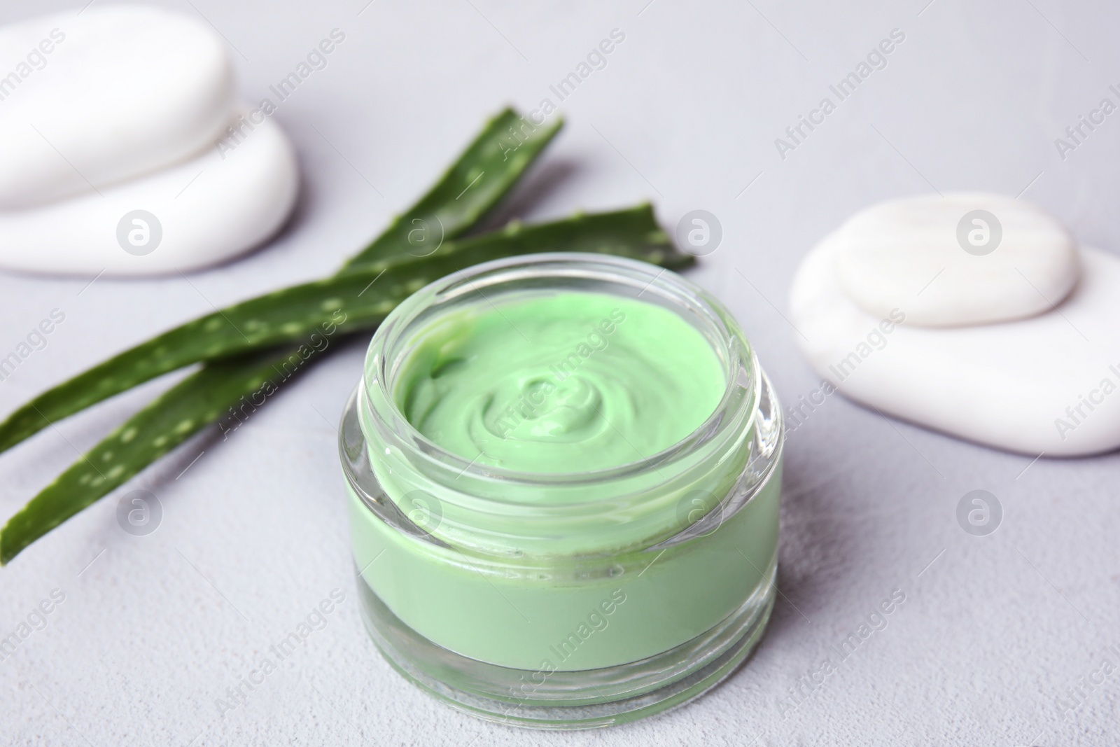 Photo of Professional face mask with spa stones and aloe on light gray table