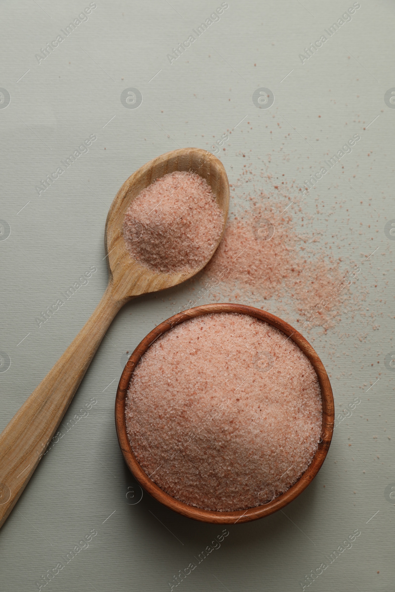 Photo of Himalayan salt in bowl and spoon on grey background, flat lay