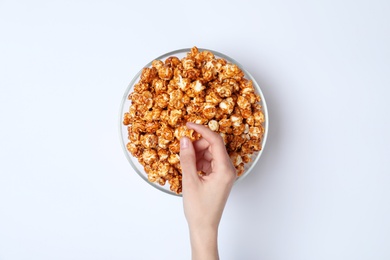 Photo of Woman eating tasty popcorn from bowl on white background, top view