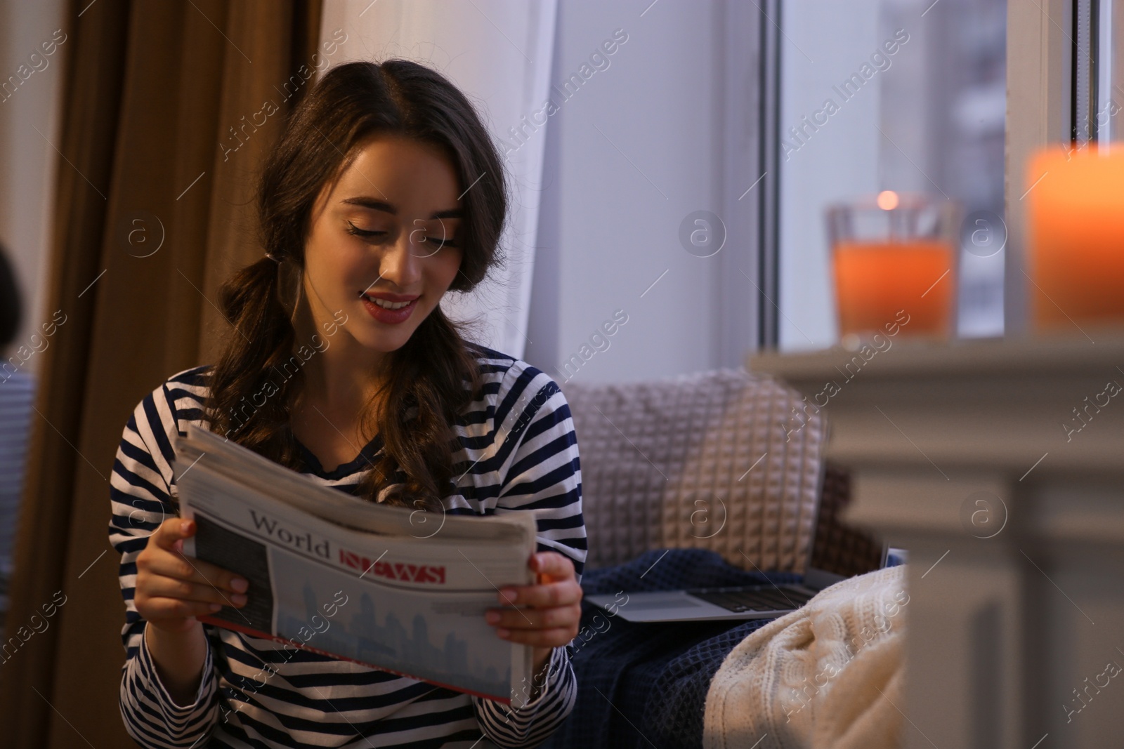 Photo of Young woman with newspaper near window at home. Winter atmosphere