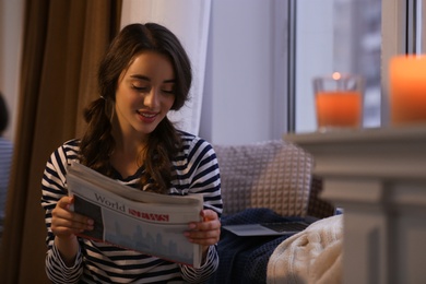 Photo of Young woman with newspaper near window at home. Winter atmosphere