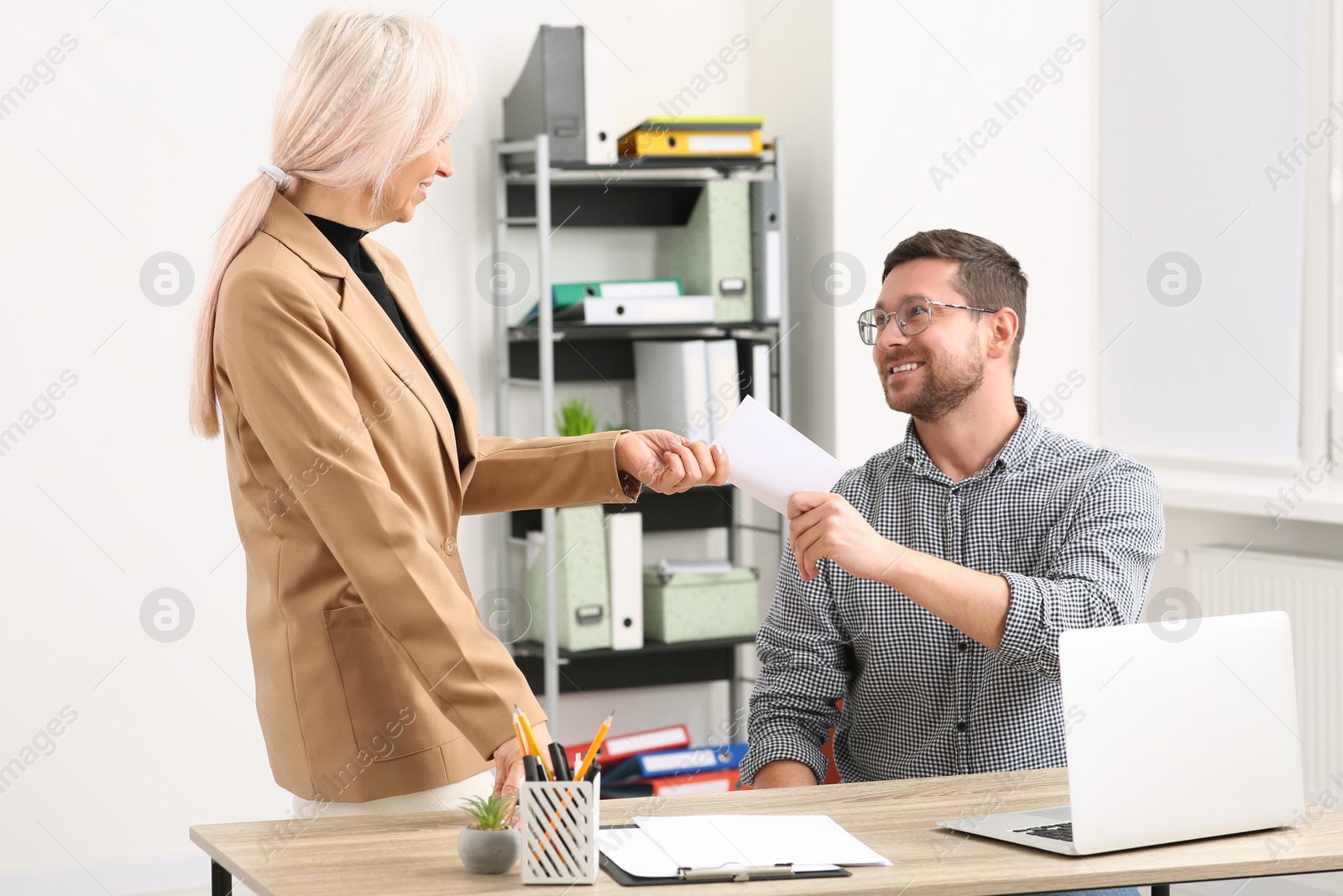 Photo of Boss giving paper card to employee in office