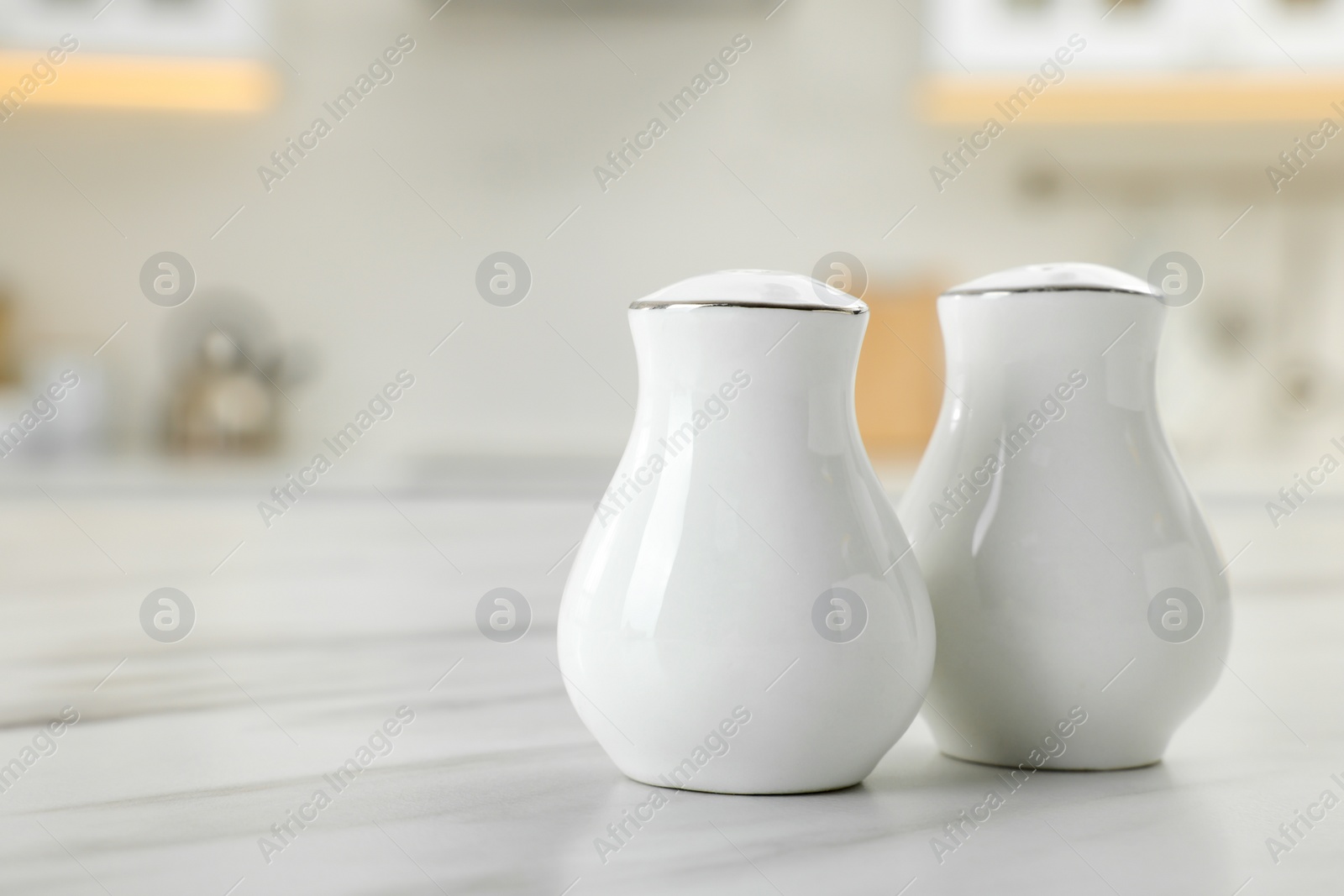 Photo of Ceramic salt and pepper shakers on white marble table in kitchen. Space for text