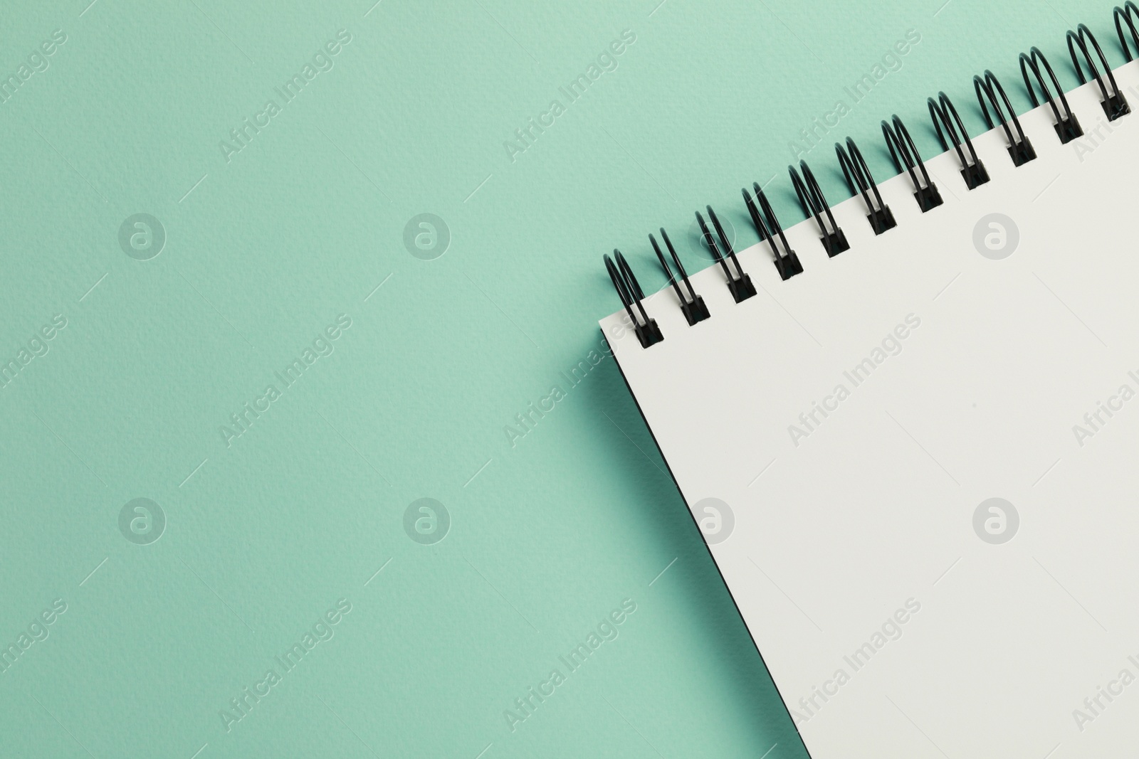 Photo of Blank notebook on turquoise background, top view. Space for text