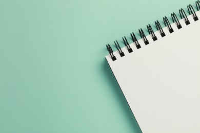 Photo of Blank notebook on turquoise background, top view. Space for text