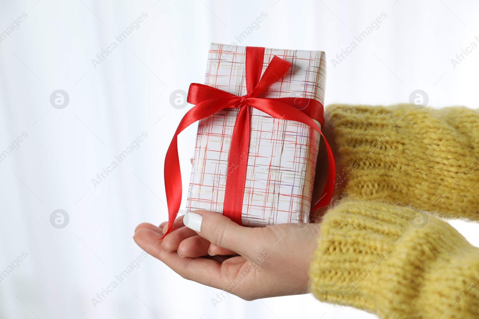 Photo of Woman in warm sweater holding Christmas gift on white background, closeup