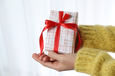 Photo of Woman in warm sweater holding Christmas gift on white background, closeup