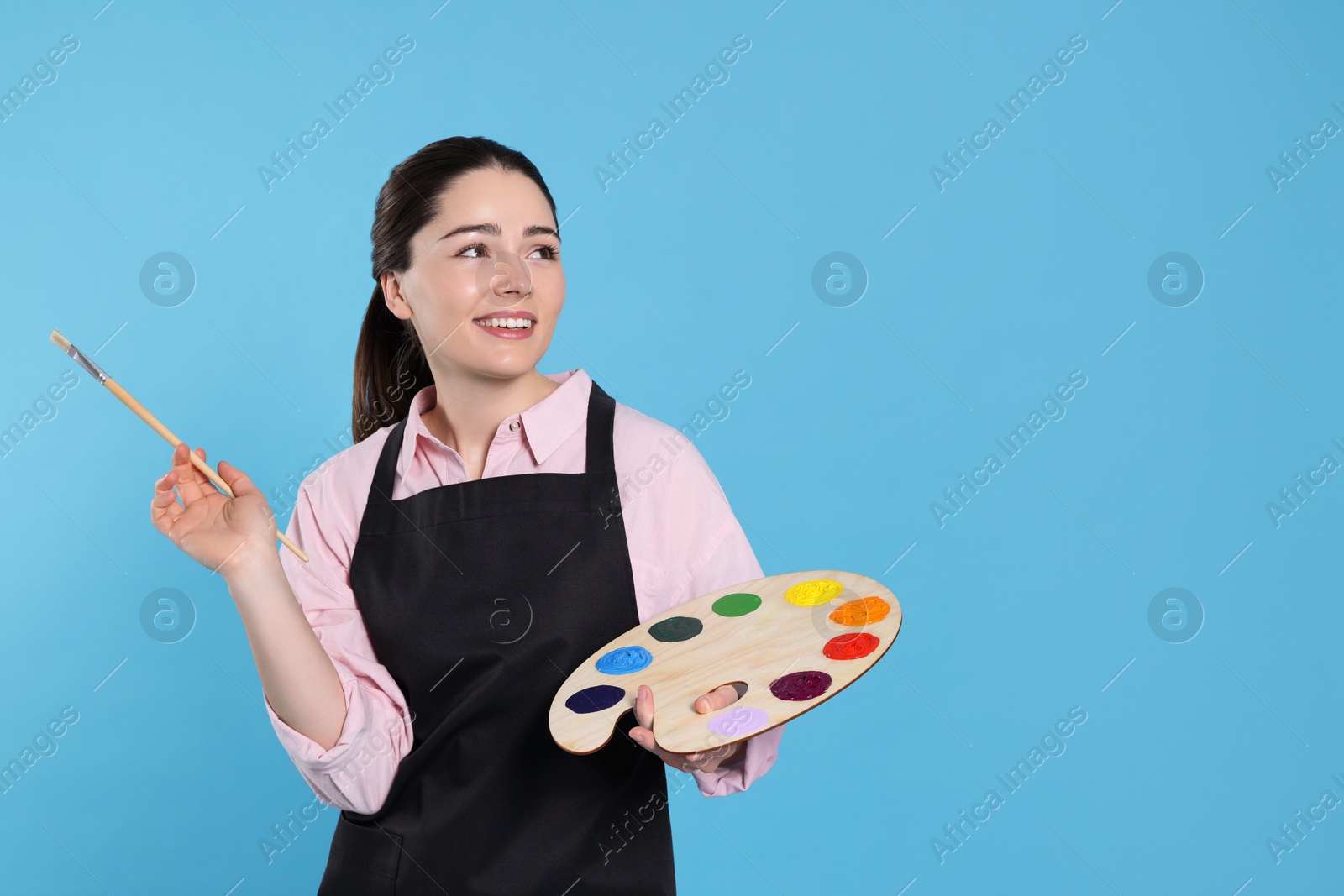 Photo of Woman with painting tools on light blue background, space for text. Young artist