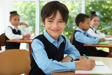 Boy wearing new school uniform in classroom