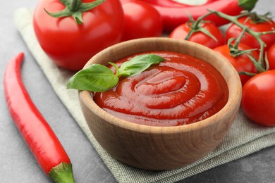 Bowl of tasty ketchup and ingredients on light grey table, closeup