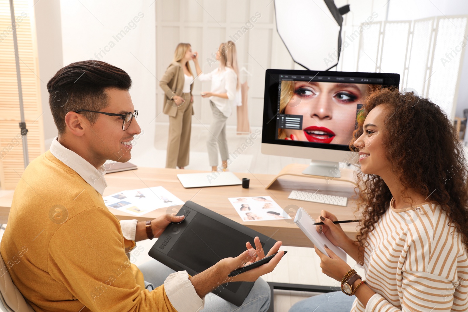 Photo of Professional retoucher with colleague working at desk in photo studio