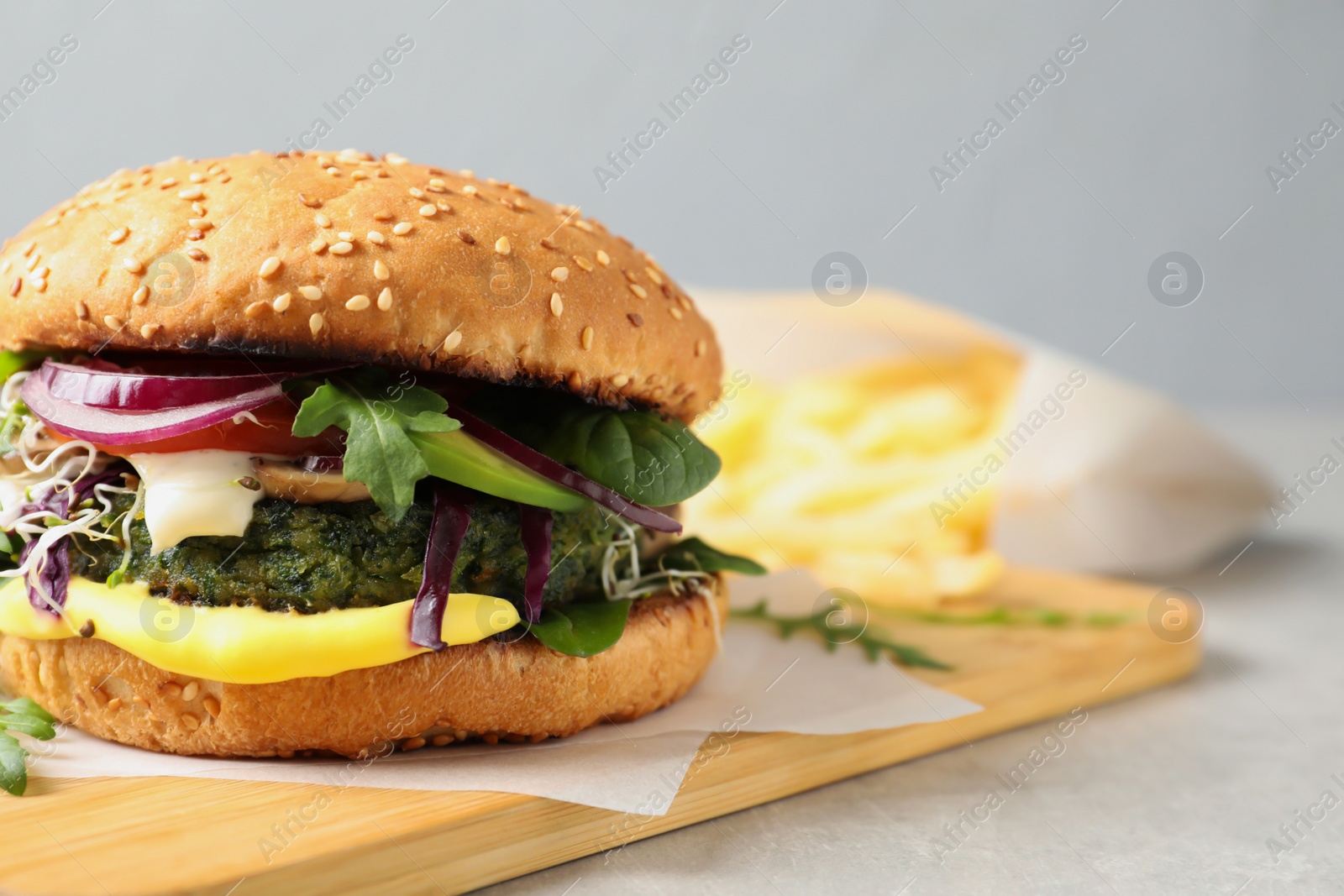 Photo of Board with tasty vegetarian burger on table. Space for text