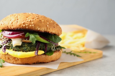 Photo of Board with tasty vegetarian burger on table. Space for text