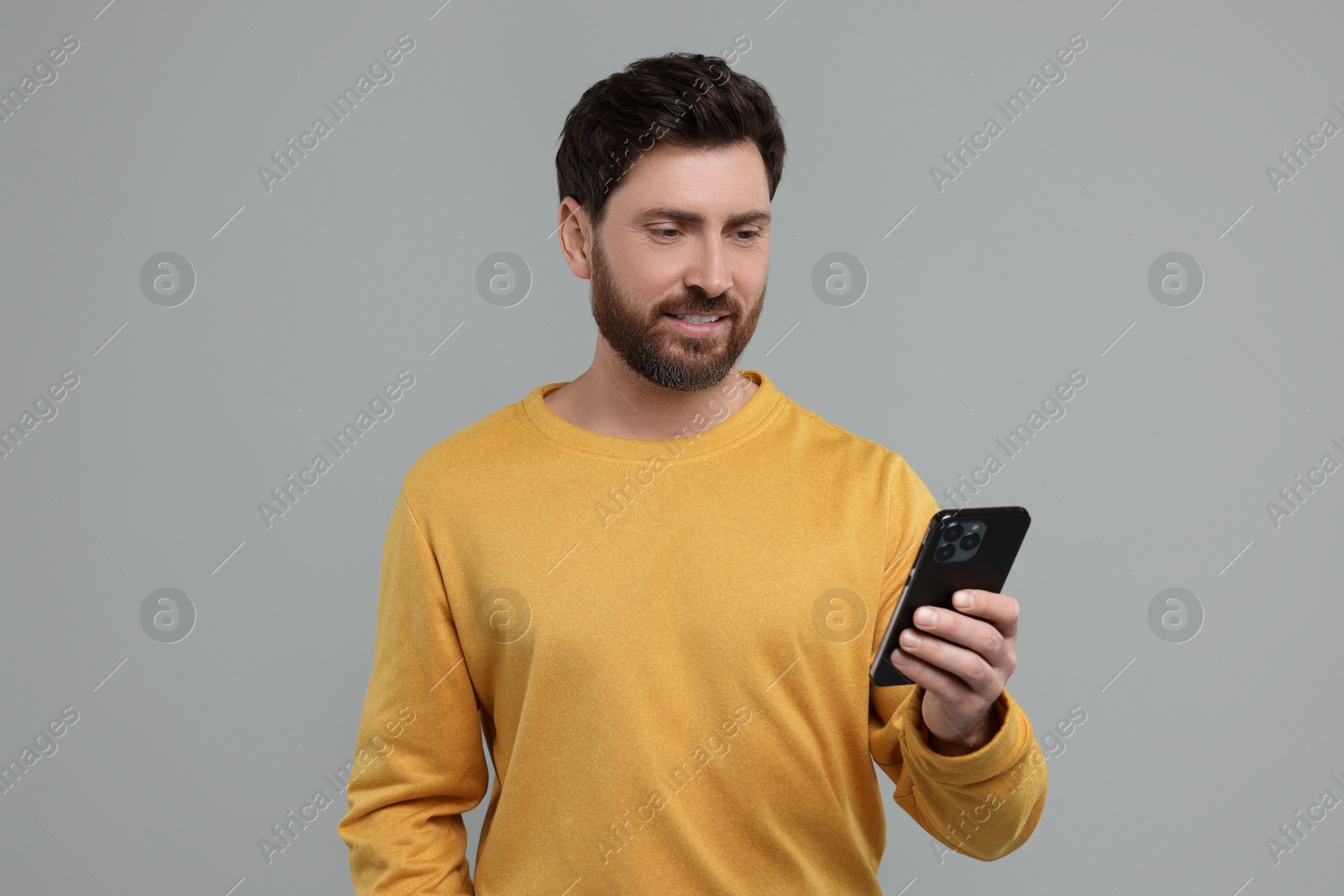 Photo of Handsome man with smartphone on grey background