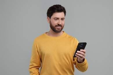 Photo of Handsome man with smartphone on grey background