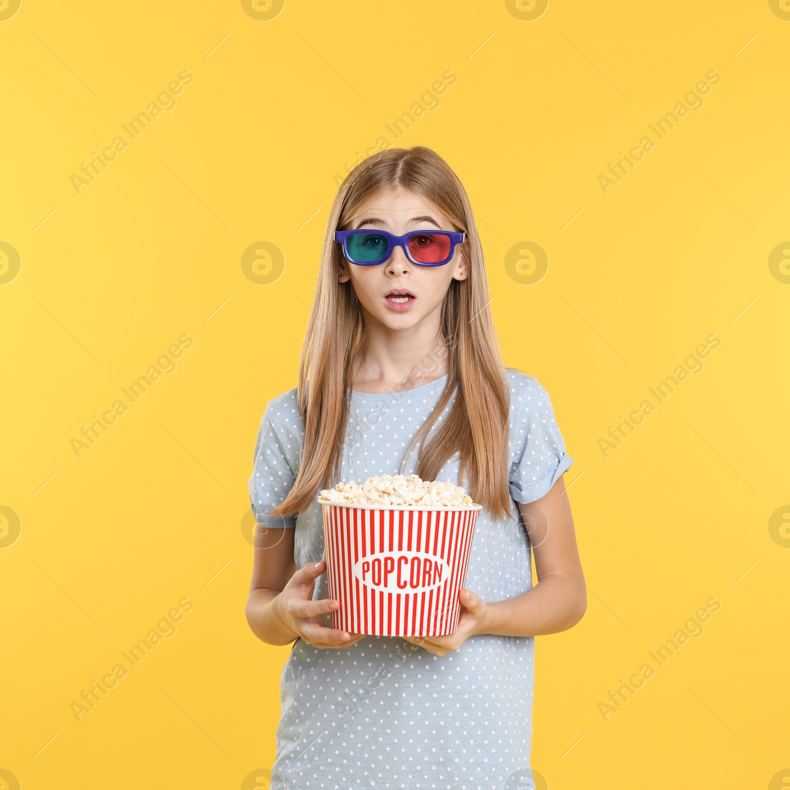 Photo of Emotional teenage girl with 3D glasses and popcorn during cinema show on color background