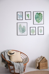 Beautiful paintings of tropical leaves on white wall in living room interior