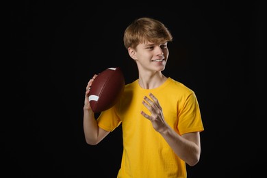 Photo of Teenage boy with american football ball on black background