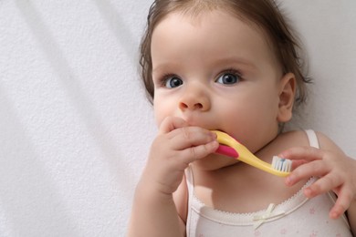 Cute little baby with toothbrush in comfortable crib, top view. Space for text