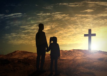 Image of Silhouettes of godparent with child in field at sunrise