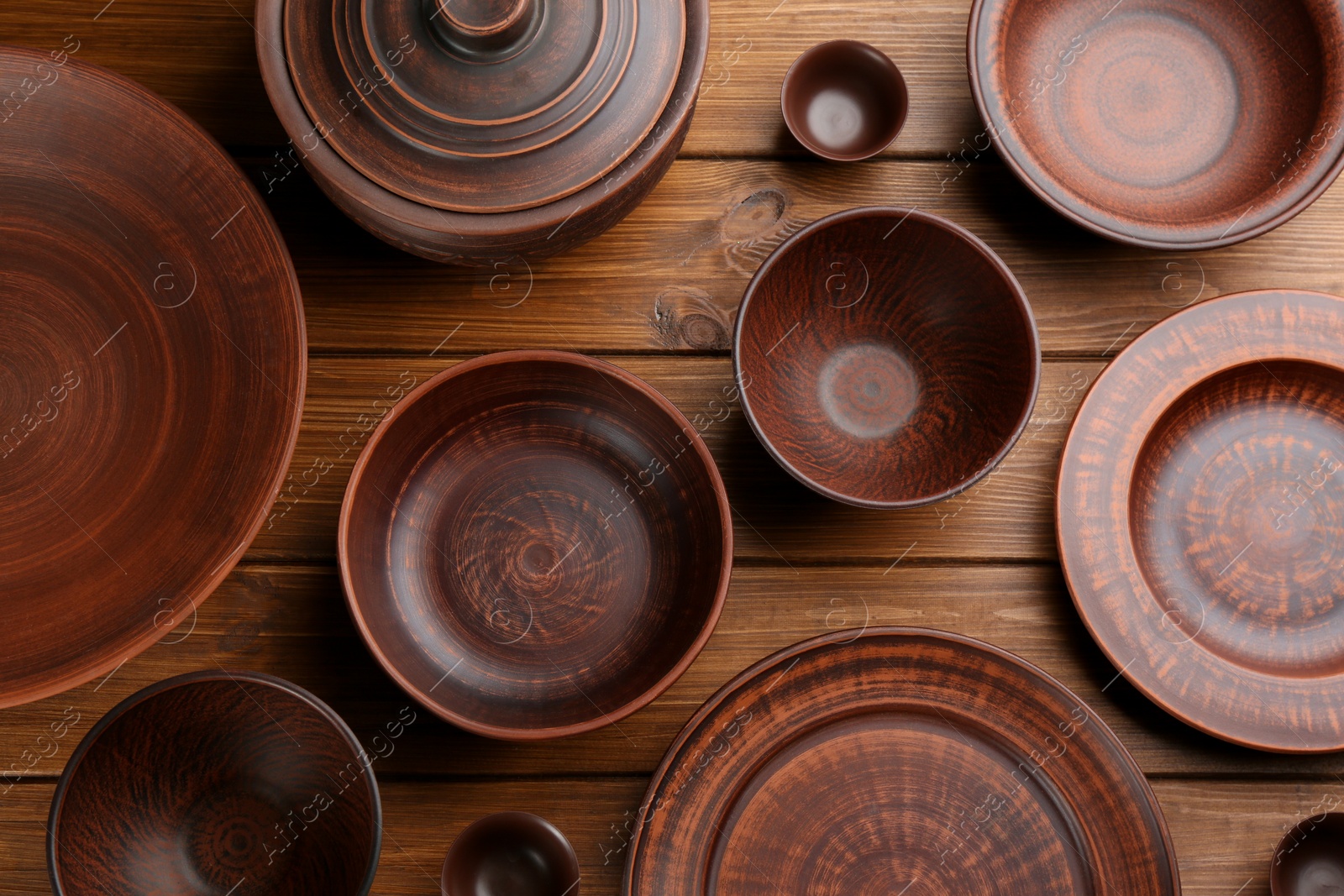 Photo of Set of clay utensils on wooden table, flat lay