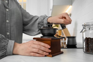 Photo of Woman using vintage coffee grinder at countertop indoors, closeup