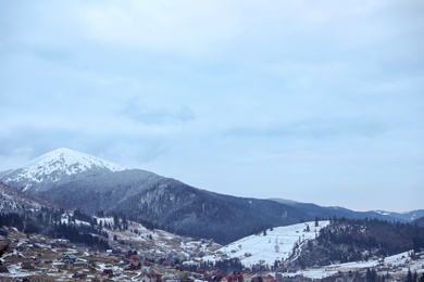 Photo of Winter landscape with mountain village near conifer forest