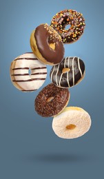 Image of Sweet tasty donuts falling on pale blue background