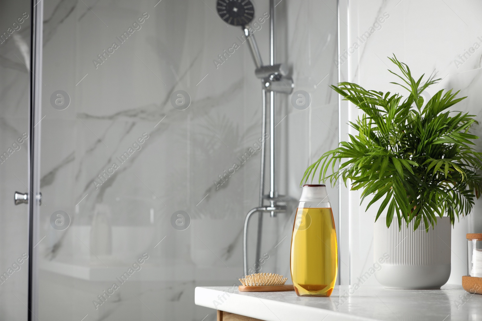 Photo of Bottle of shampoo and hairbrush on white table near shower stall in bathroom, space for text