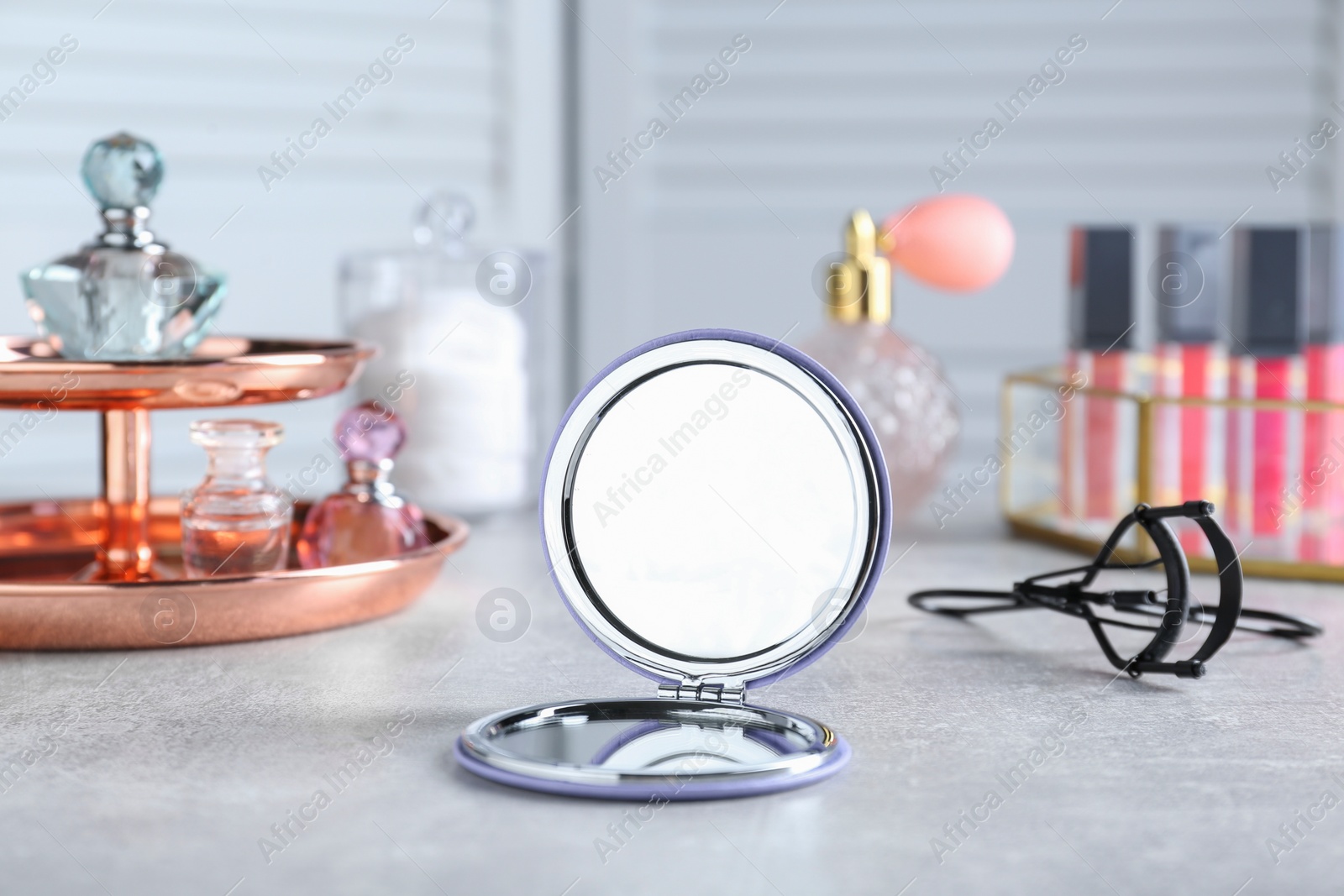 Photo of Stylish pocket mirror and cosmetic products on grey table