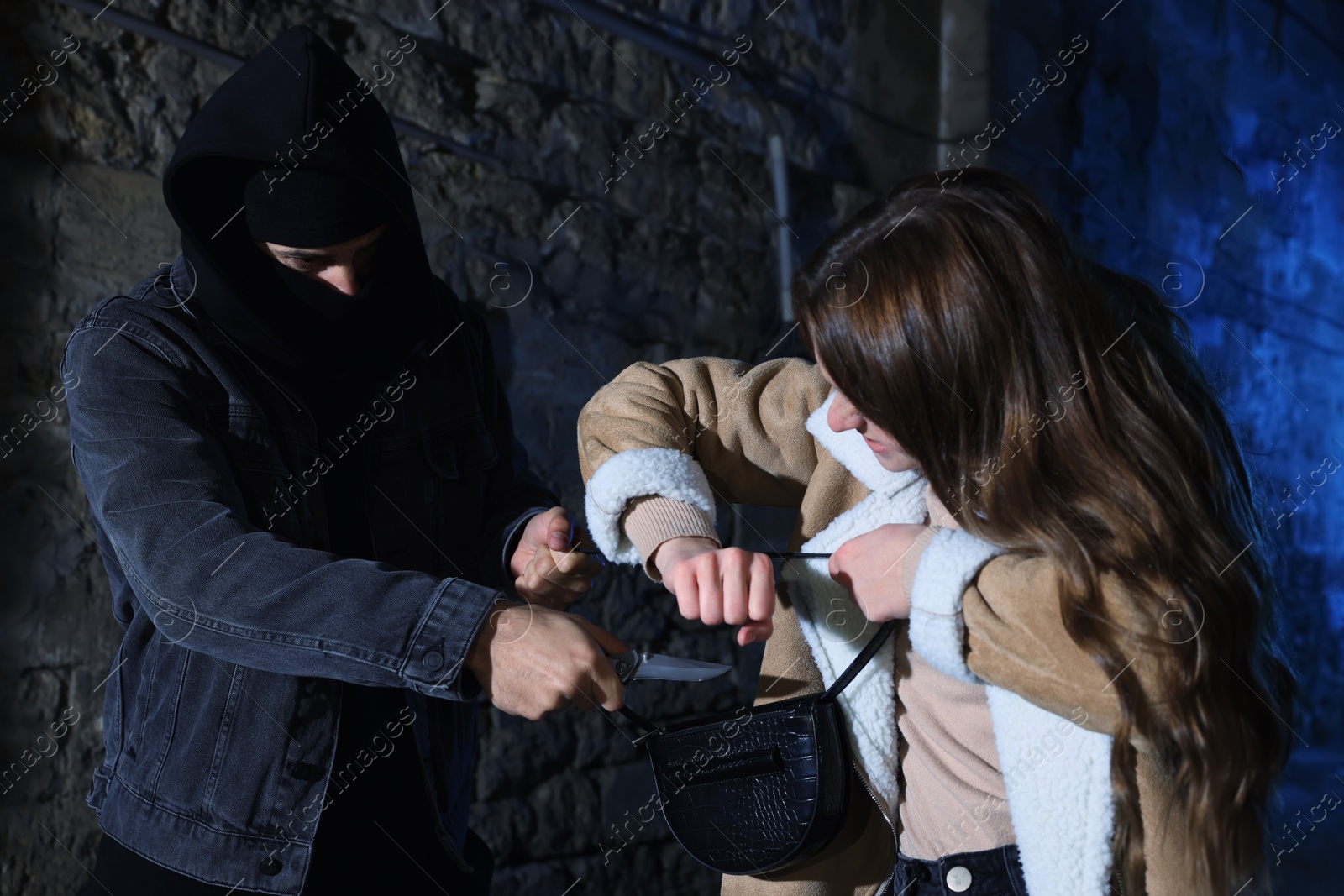 Photo of Woman fighting with thief while he trying to steal her bag in alley at night. Self defense concept