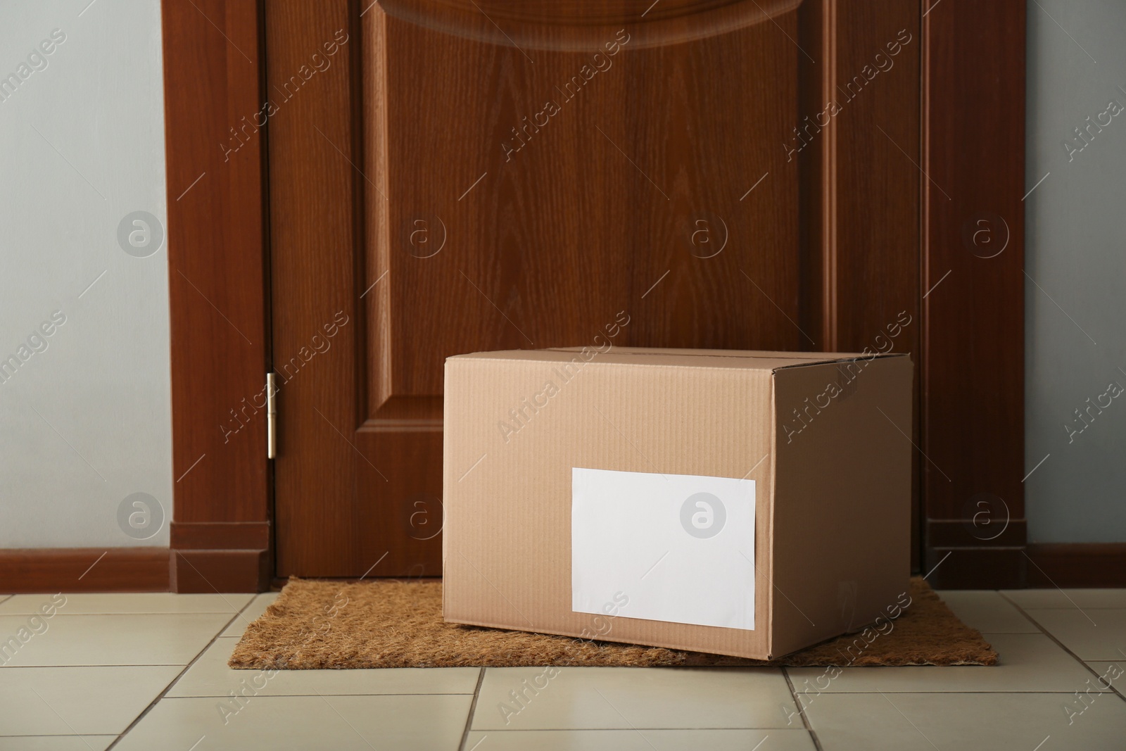 Photo of Parcel on rug near door. Delivery service