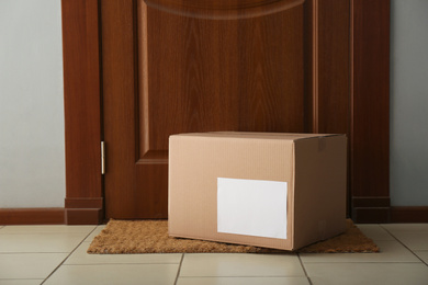 Photo of Parcel on rug near door. Delivery service