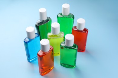 Fresh mouthwashes in bottles on light blue background