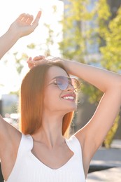 Photo of Beautiful smiling woman in sunglasses outdoors on sunny day