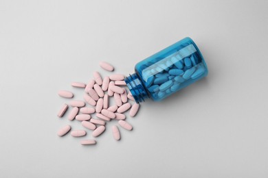 Vitamin pills and bottle on grey background, top view