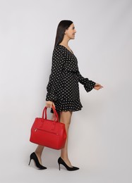 Young woman with stylish bag on white background,