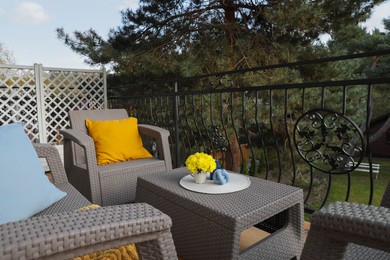 Photo of Colorful pillows and yellow chrysanthemum flowers on rattan garden furniture outdoors