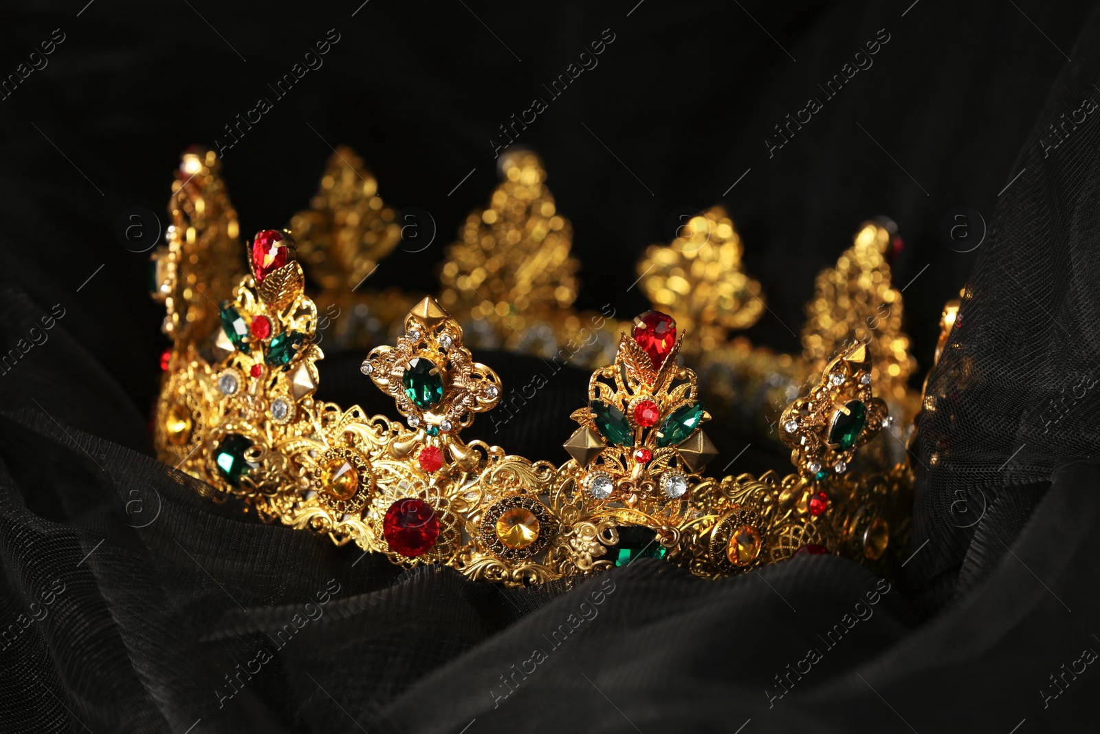 Photo of Beautiful golden crown with gems on black cloth