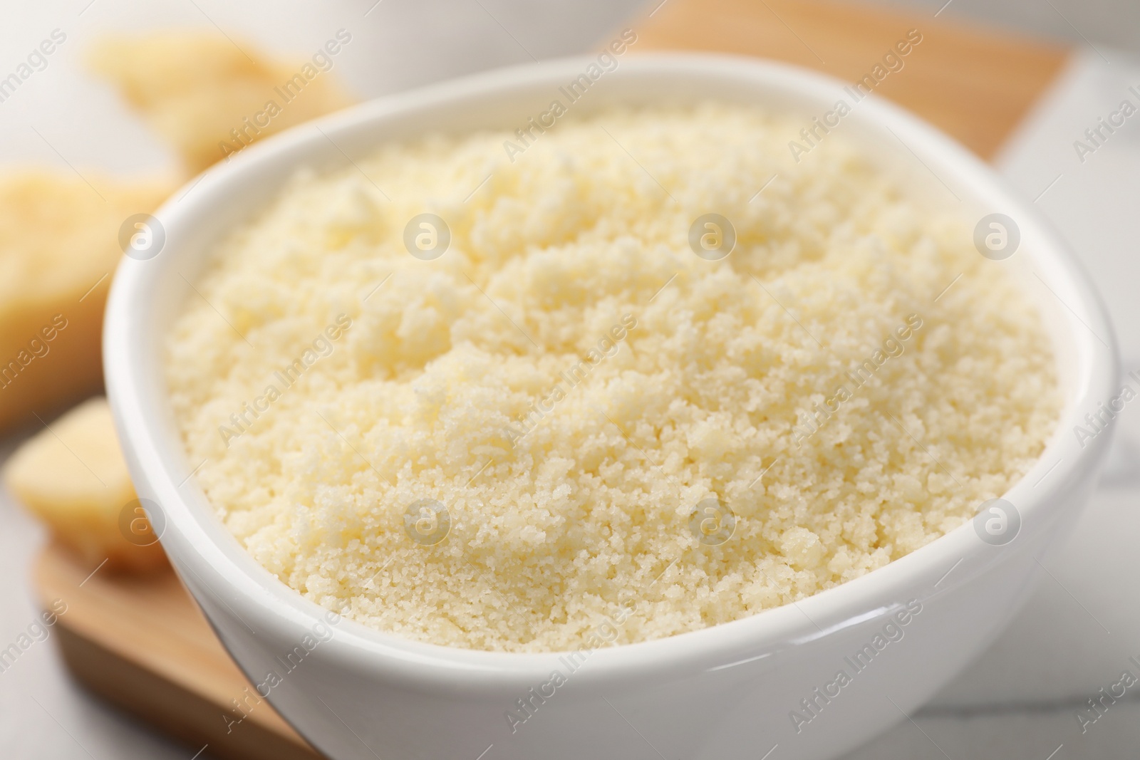 Photo of Bowl with grated parmesan cheese on table, closeup